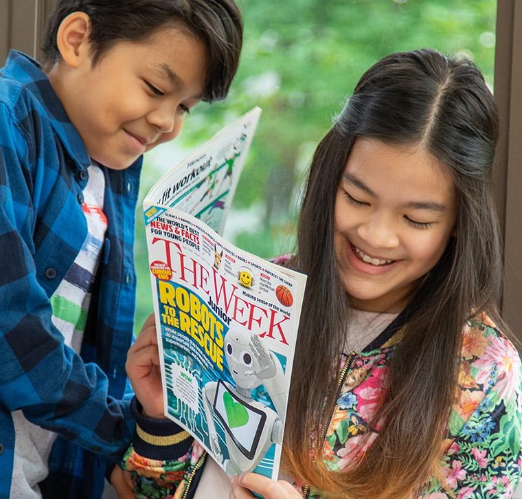 A boy and a girl reading The Week Junior magazine