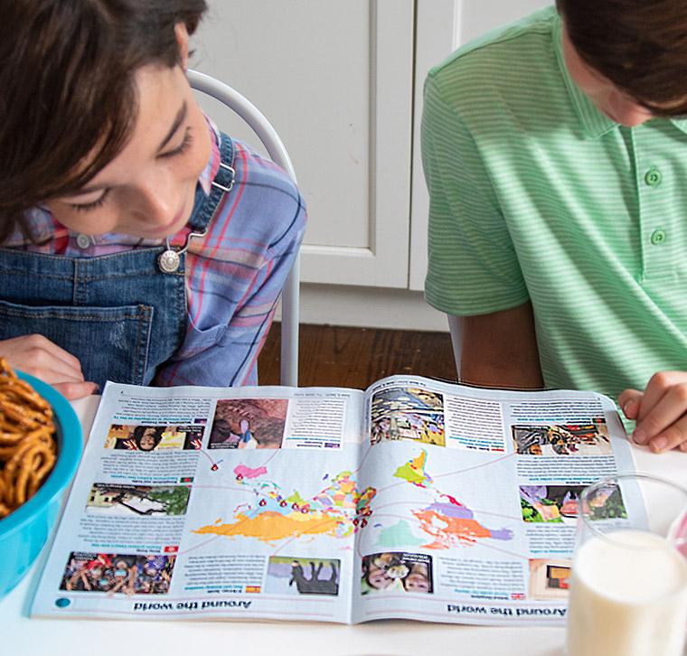 Two children reading an issue of The Week Junior together